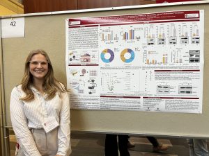 Hailee Porter standing beside her research poster at UW-Madison Pathology Research Day